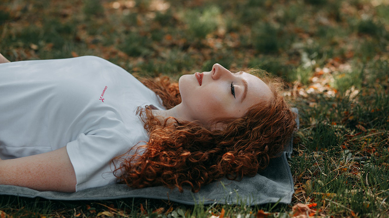 Woman resting on the ground peacefully in yoga corpse pose